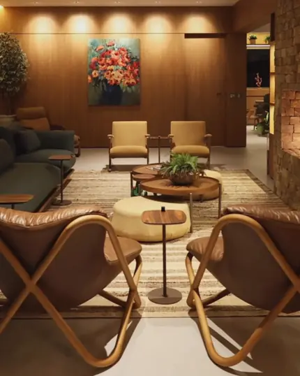 Casa Bem-te-vi: sala com poltronas de couro, pufe redondo e tela de flores ao fundo