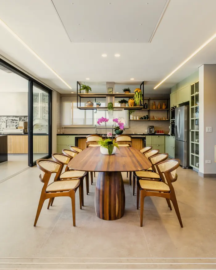 Sala de jantar com mesa de madeira de base esculpida, cadeiras de madeira e estante com objetos