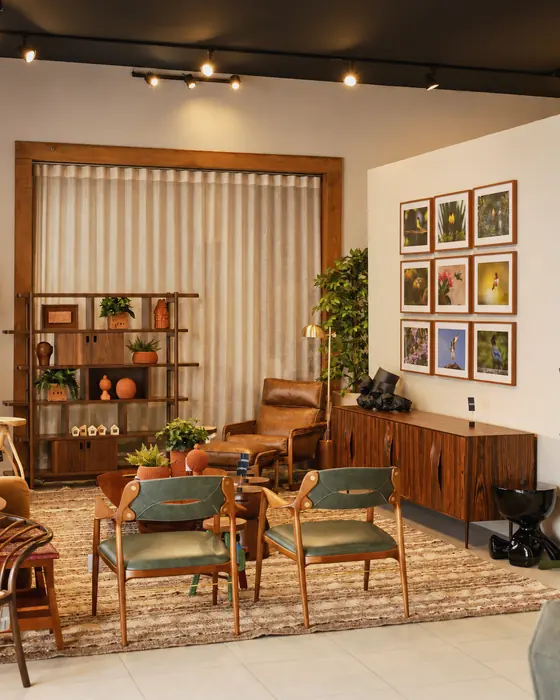 Showroom DRØM: cadeiras de madeira com assento verde, estante com cerâmicas e quadros de pássaros